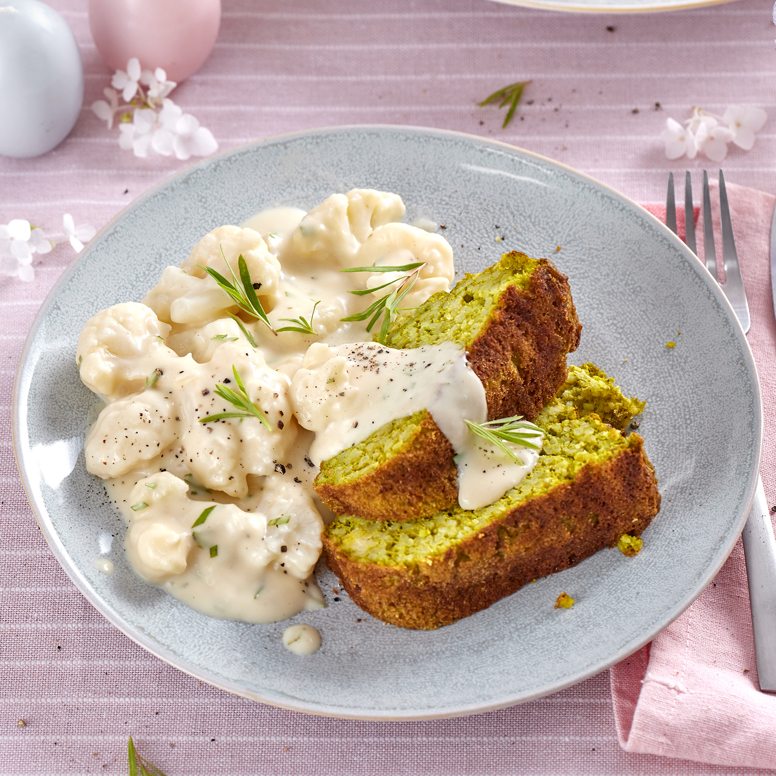 Grüner Hirsegugelhupf mit Blumenkohl in Estragon-Sahnesoße auf einem Teller.