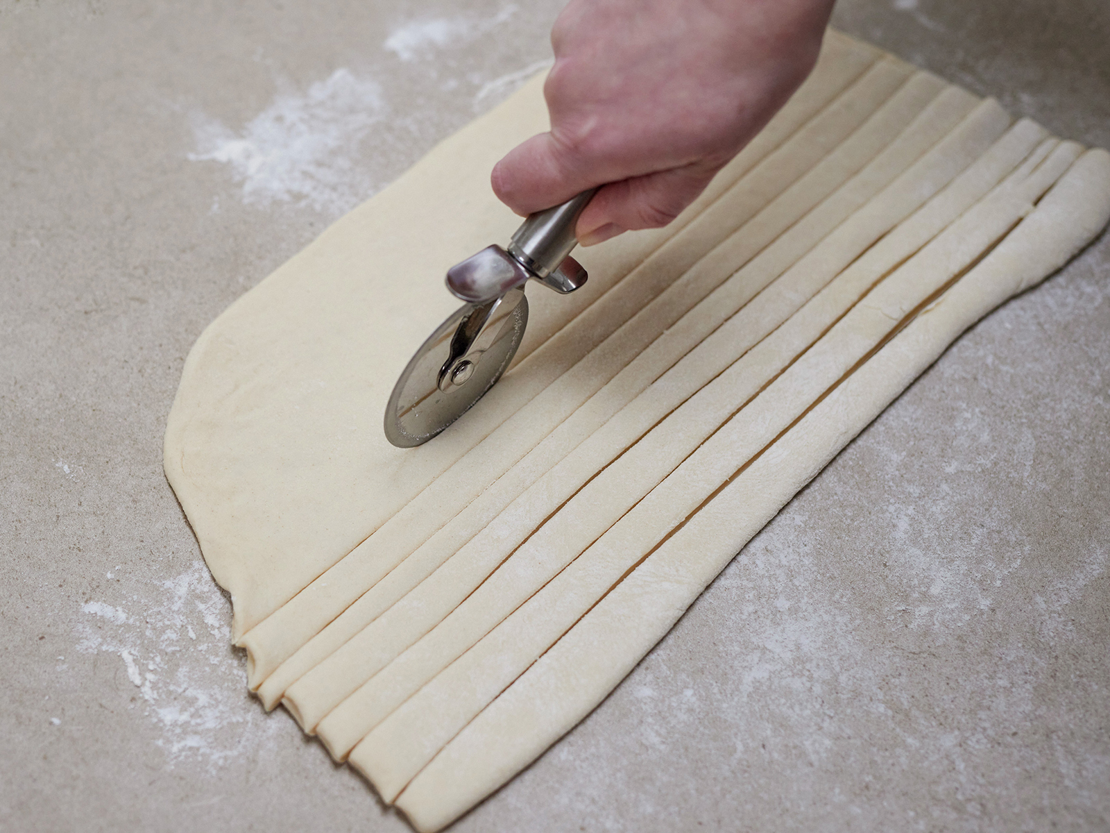 Der Teig wird längs in Streifen geschnitten.