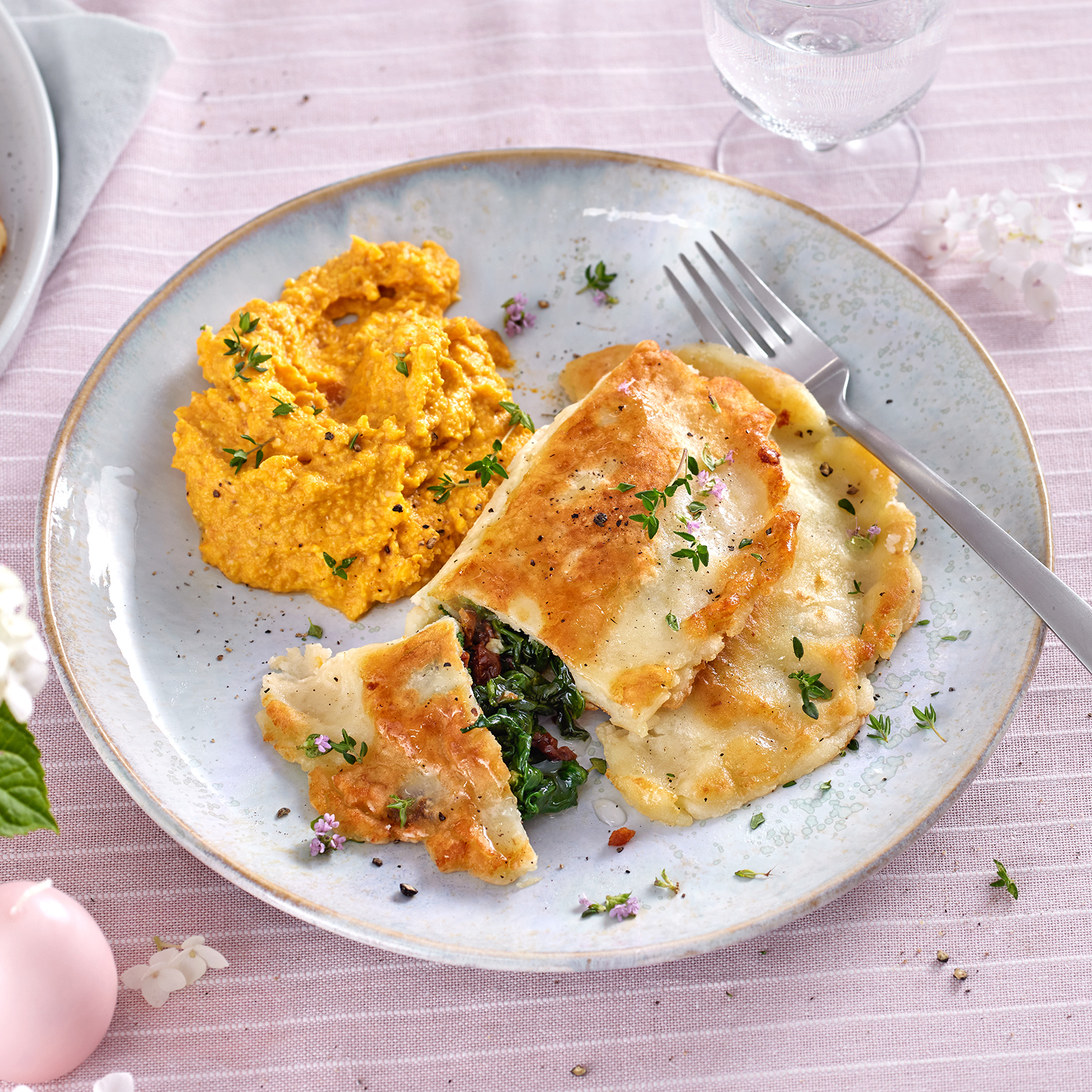 Kartoffel-Calzone mit Spinatfüllung und Möhren-Walnuss-Creme auf einem Teller.