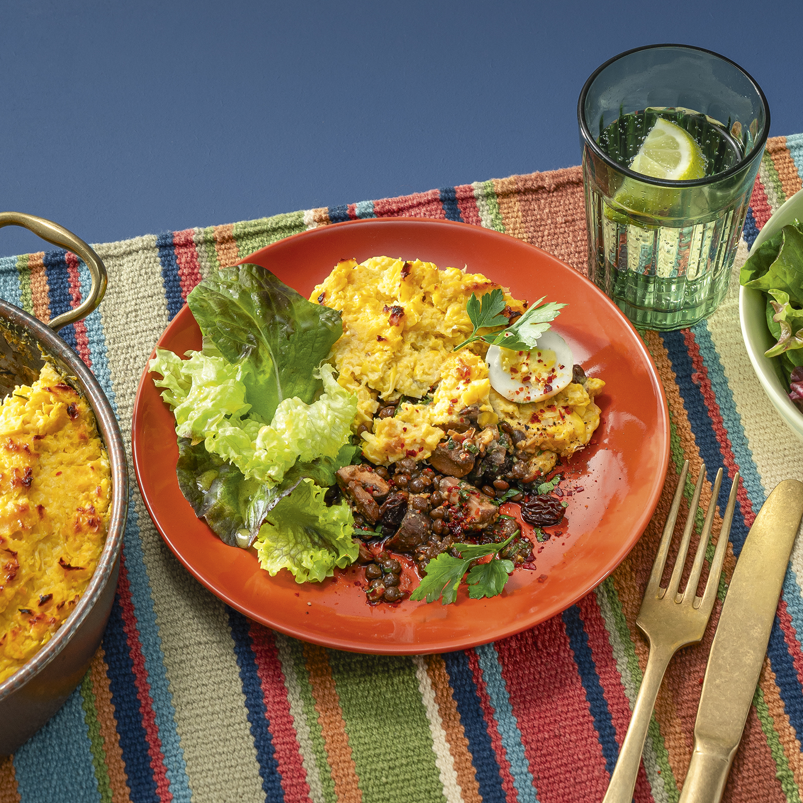 Maisauflauf mit Linsen-Pilz-Füllung und grünem Salat, angerichtet auf einem Teller.