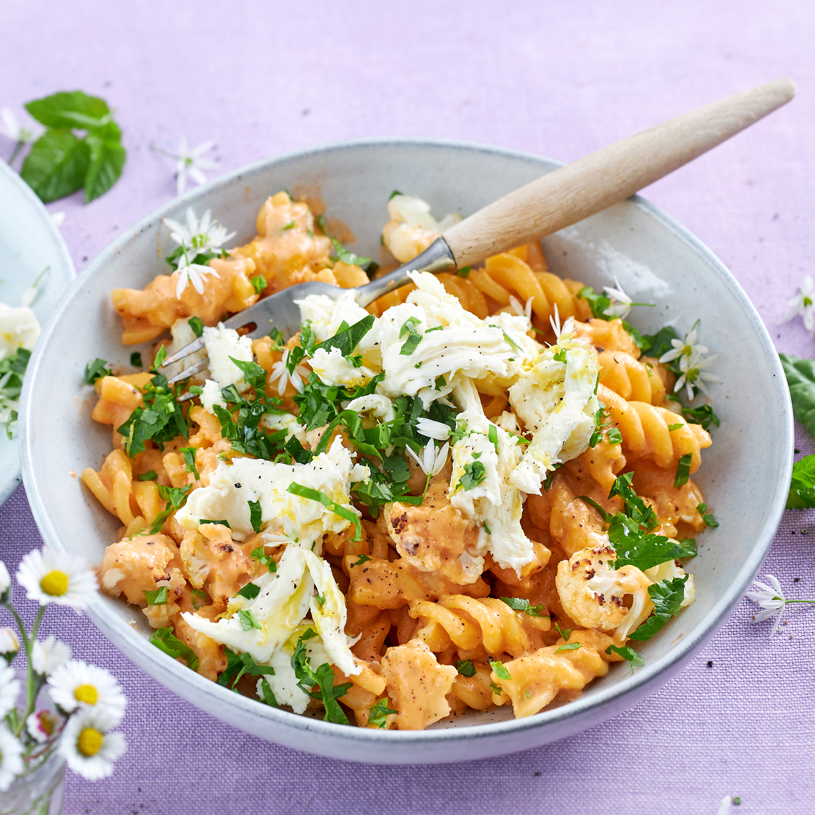Pasta mit Blumenkohl und Wildkräuter-Mozzarella in einer Schale, garniert mit Bärlauch-Blüten.