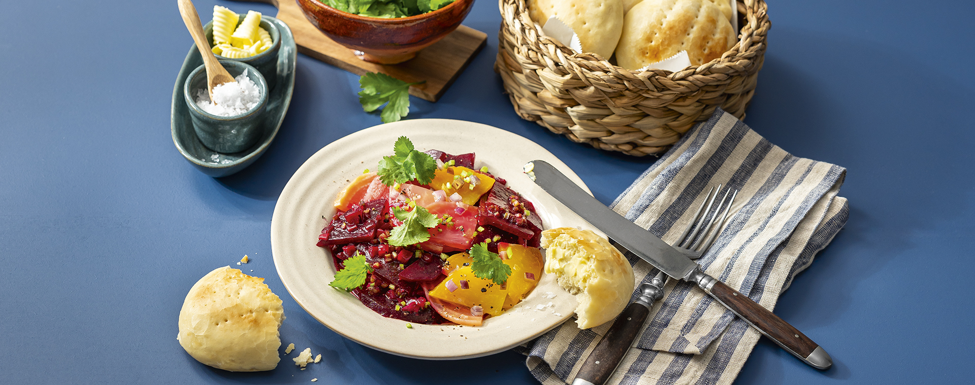 Rote-Bete-Salat mit frischem Koriander in einem tiefen Teller, dazu Weizenbrötchen mit Butter und Salz.