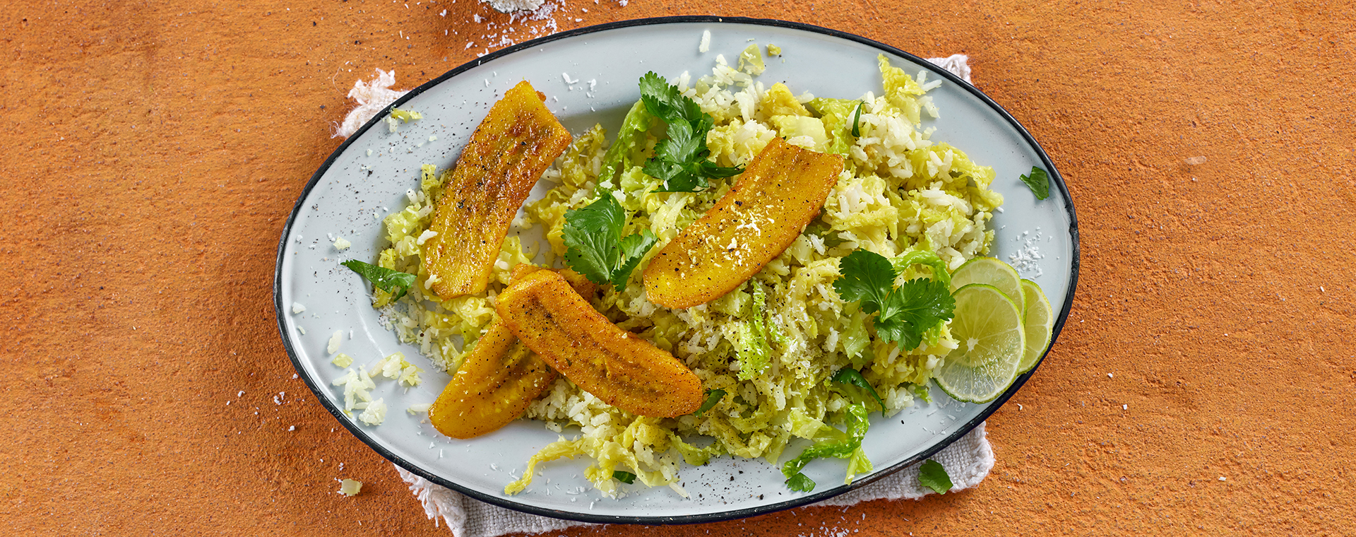 Wirsing-Kokos-Reis mit Currybananen und Koriander auf einem Teller.